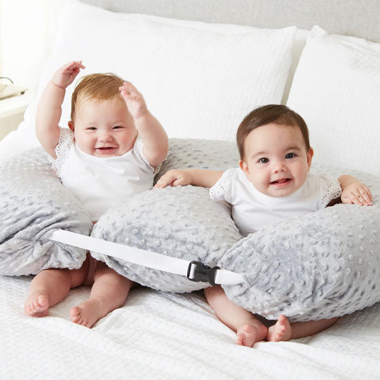 2 bebes assis dans coussin d allaitement twincuddle gris