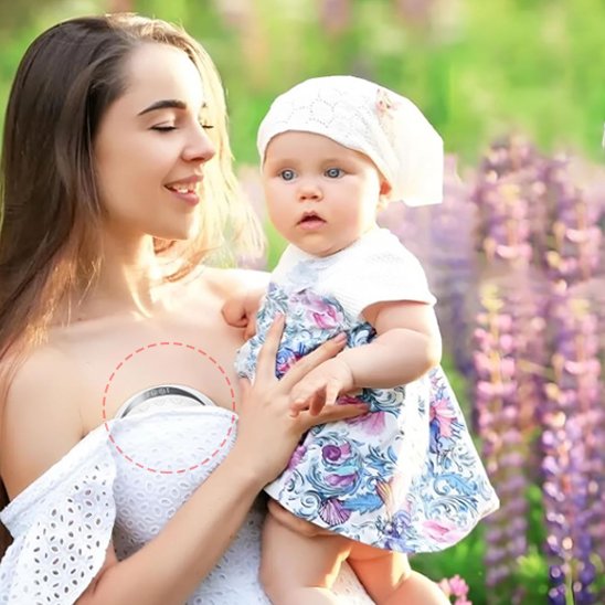 femme en robe dehors utilisant tire lait electrique main libre automatique avec bebe dans les bras