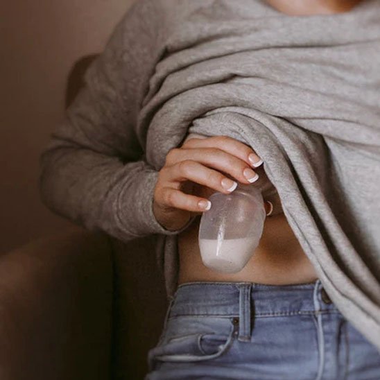 femme tient tire-lait collecteur sous son chandail