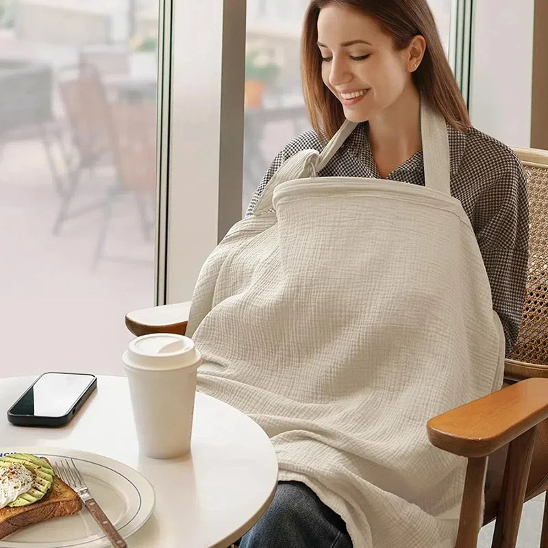 maman allaite dans un café avec cape d'allaitement mousseline