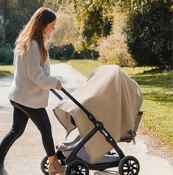 maman promène bébé en poussette avec cape d'allaitement mousseline
